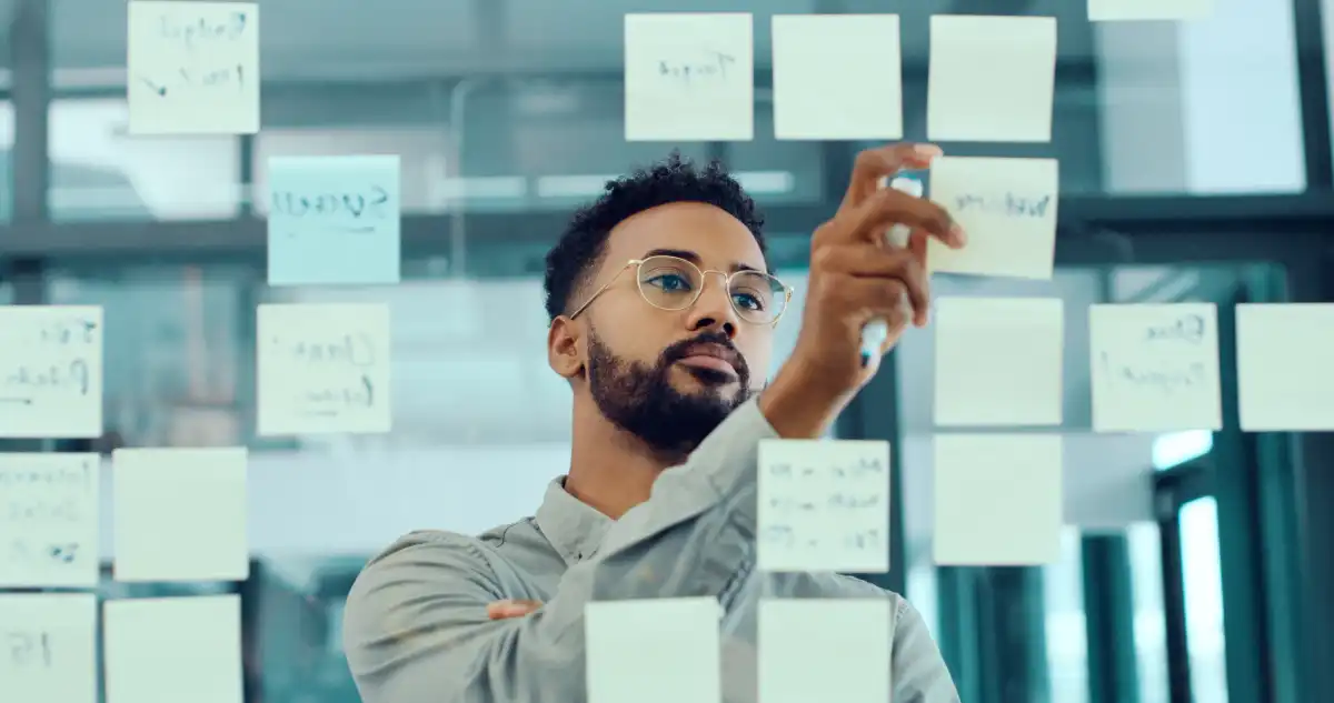 Businessman brainstorming with sticky notes on a glass wall